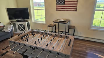 Une pièce avec une table de baby-foot, un téléviseur et un drapeau.
