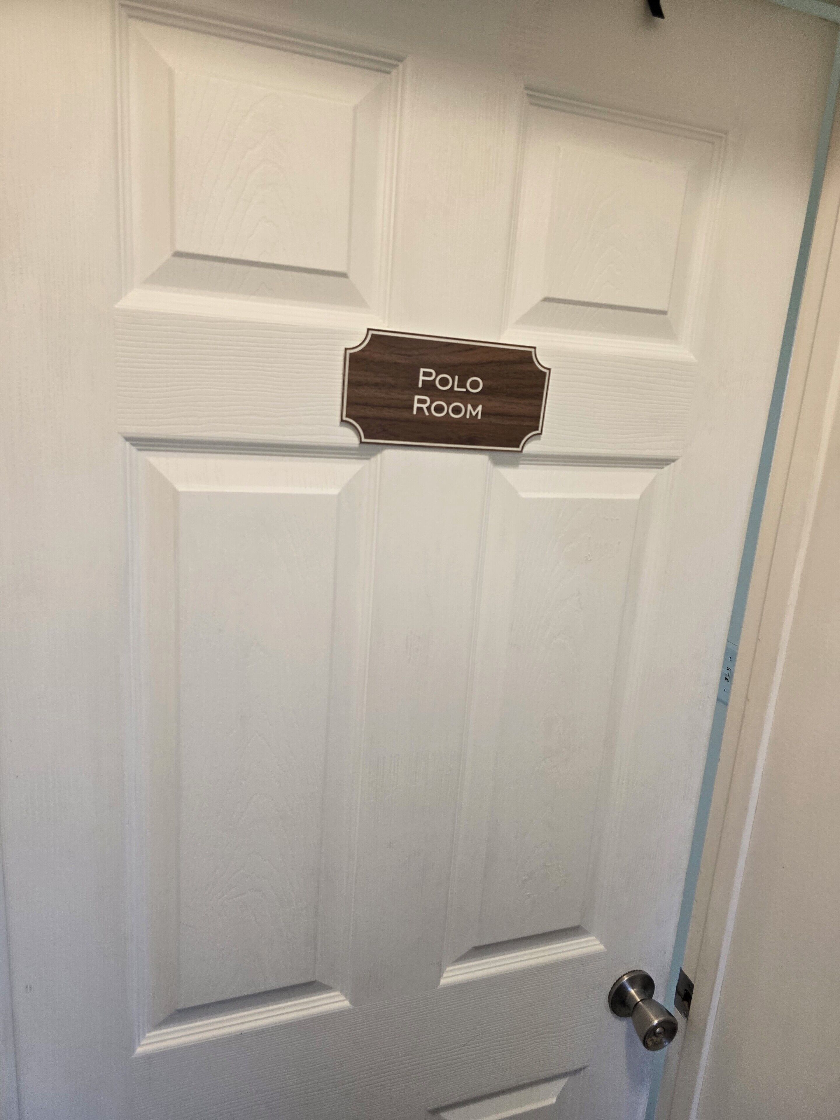 Une porte blanche avec une enseigne indiquant « SALLE POLO » au-dessus.