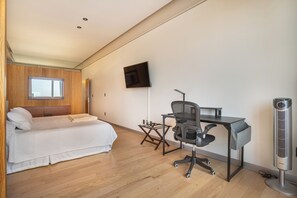 Ein modernes Schlafzimmer mit Bett, Schreibtisch, Stuhl und einem an der Wand befestigten Fernseher.