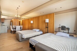 Habitación de hotel con dos camas, un escritorio, una silla, una lámpara y un panel de pared de madera.