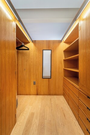 Ein begehbarer Kleiderschrank mit Holzwänden und Holzböden, ausgestattet mit Kleiderstange, Regalen und Schubladen.