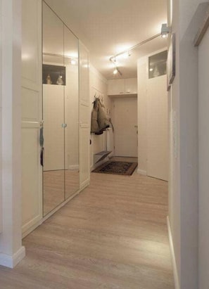 Ein Flur mit einem Spiegelkleiderschrank, einem Kleiderständer und einem kleinen Teppich.