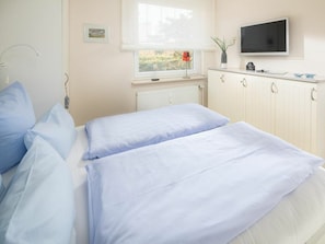 Ein Schlafzimmer mit zwei Betten, einem Fenster mit Blick, einem Flachbildfernseher und einer Heizung.