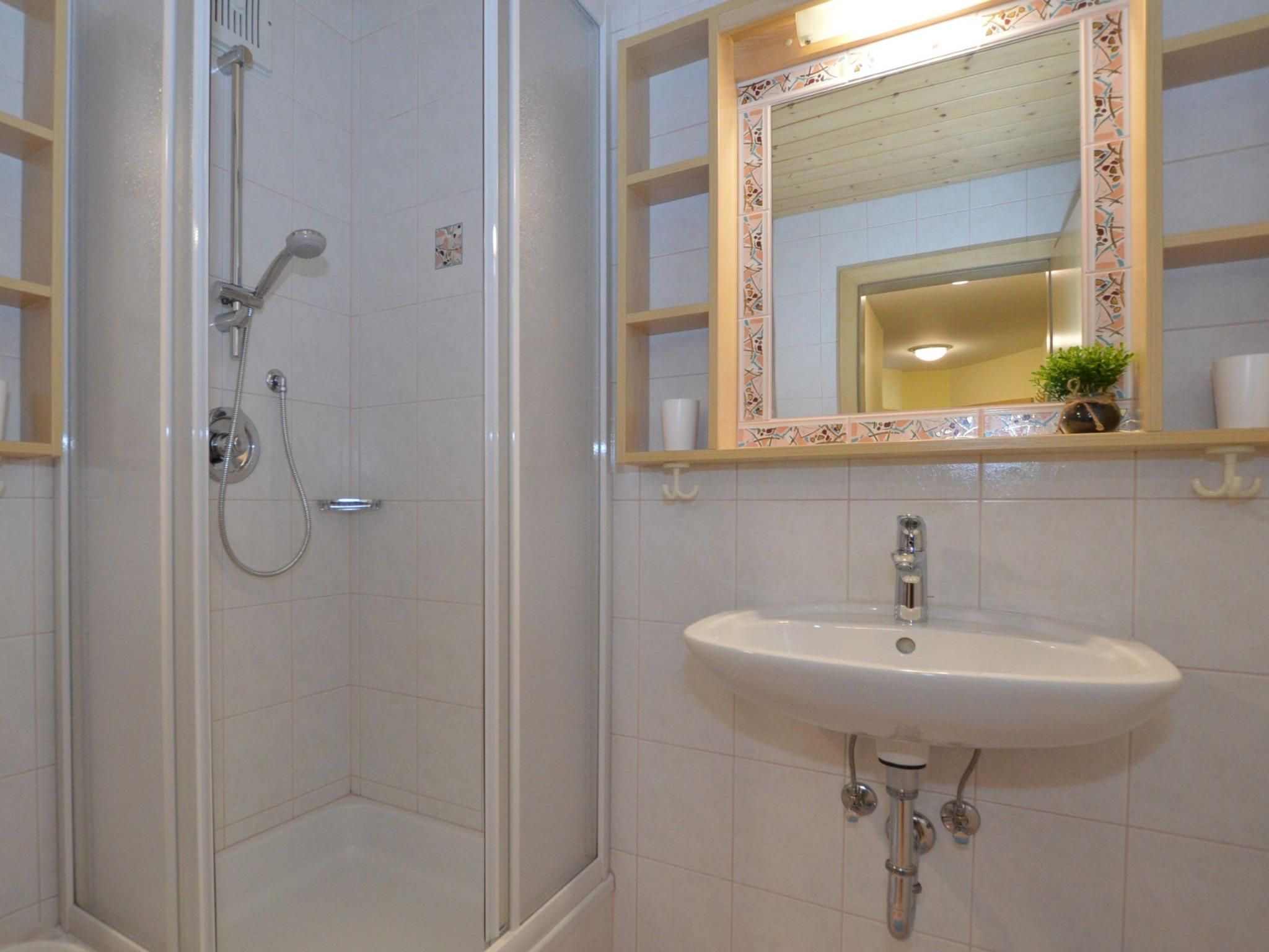 Ein Badezimmer mit Dusche, Waschbecken und einem Spiegel mit Zierrahmen.