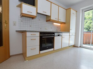A kitchen with white cabinets, a built-in oven, and a window providing natural light. - A warm nest as your home in the mountains (Wagrain)