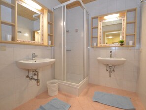 Un baño con dos lavamanos, una ducha y un espejo.