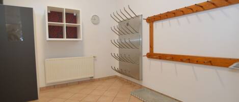 A room with a tiled floor, a radiator, a window with red curtains, and a wall-mounted coat rack.