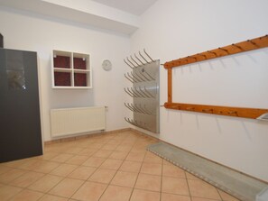 A room with a tiled floor, a radiator, a window with red curtains, and a wall-mounted coat rack. - A warm nest as your home in the mountains (Wagrain)