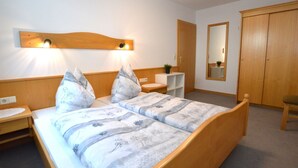 A bedroom with a wooden bed, bedside tables, a nightstand, a mirror, and a wardrobe. - A warm nest as your home in the mountains (Wagrain)