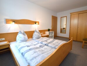 Une chambre à coucher avec un lit en bois, des tables de chevet, une commode, un miroir et une armoire.