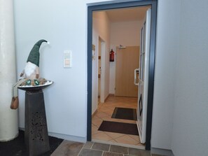 A hallway with a gnome statue on a pedestal, a fire extinguisher, and a door leading to another room. - House with last ski descent around the corner (Wagrain)