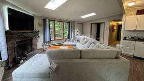 Una sala de estar con chimenea, un sofá grande y un televisor.
