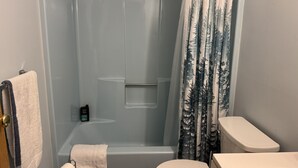 Un baño con ducha envuelta en vidrio, inodoro y perchero para toallas.