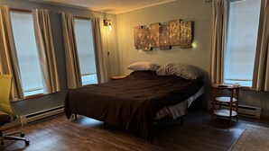 Un dormitorio con una cama, una silla, una mesita de noche y una lámpara de pared.