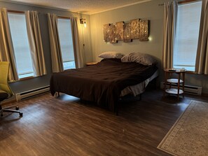 Una camera da letto con un letto, una sedia, un comodino e una lampada a parete.