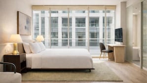 A modern hotel room with a large bed, bedside lamps, a desk, and a television. - The Emberline Hotel (Toronto)