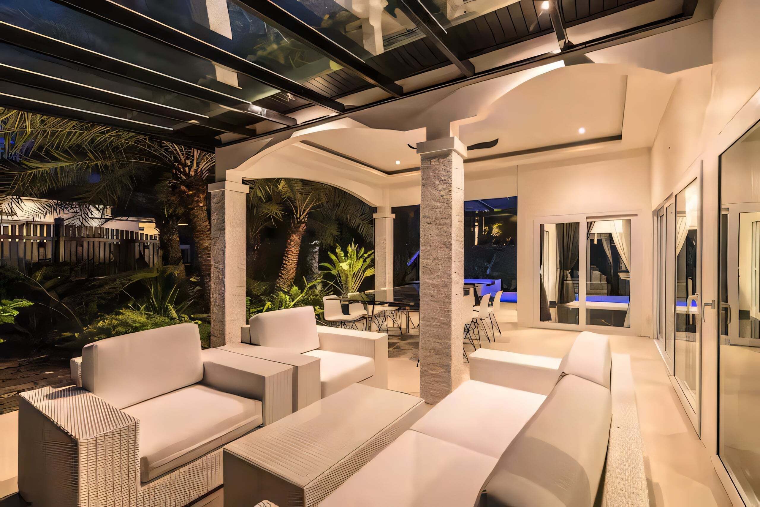An indoor-outdoor living area with modern furniture, a glass enclosure, and a view of the outdoors.