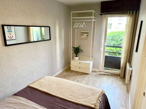 A bedroom with a bed, a bedside table, a mirror, a wardrobe, and a sliding glass door to a balcony. - Penon · 2 ch · Plage à pied, vélo, calme & repos (Seignosse)