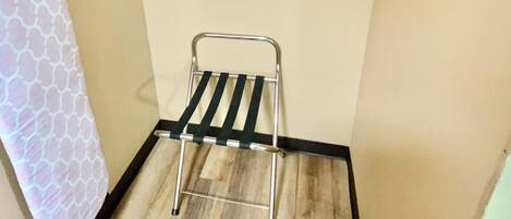 A small room with a wooden floor, a metal drying rack, and a towel hanging on the wall.