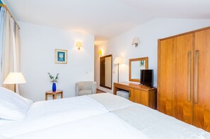 A hotel room with two beds, a desk with a TV, a chair, a wardrobe, and a mirror. - Pansion Srebreno - Double or Twin Room With Balcony and City View 3 (Zupa dubrovacka)