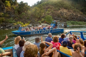 A boat tour with passengers enjoying the view of a river and surrounding landscape.