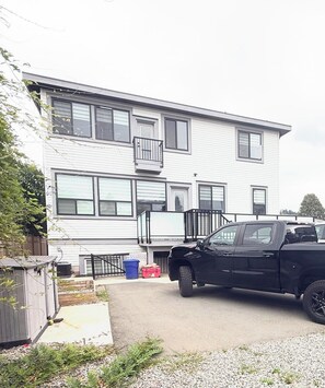 A two-story building with a garage and a black pickup truck parked in front. -     Cozy 2-Bedroom Suite/EV Charging & Parking (Mission)