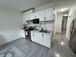A modern kitchen with white cabinets, stainless steel appliances, and a marble countertop. -     Cozy 2-Bedroom Suite/EV Charging & Parking (Mission)