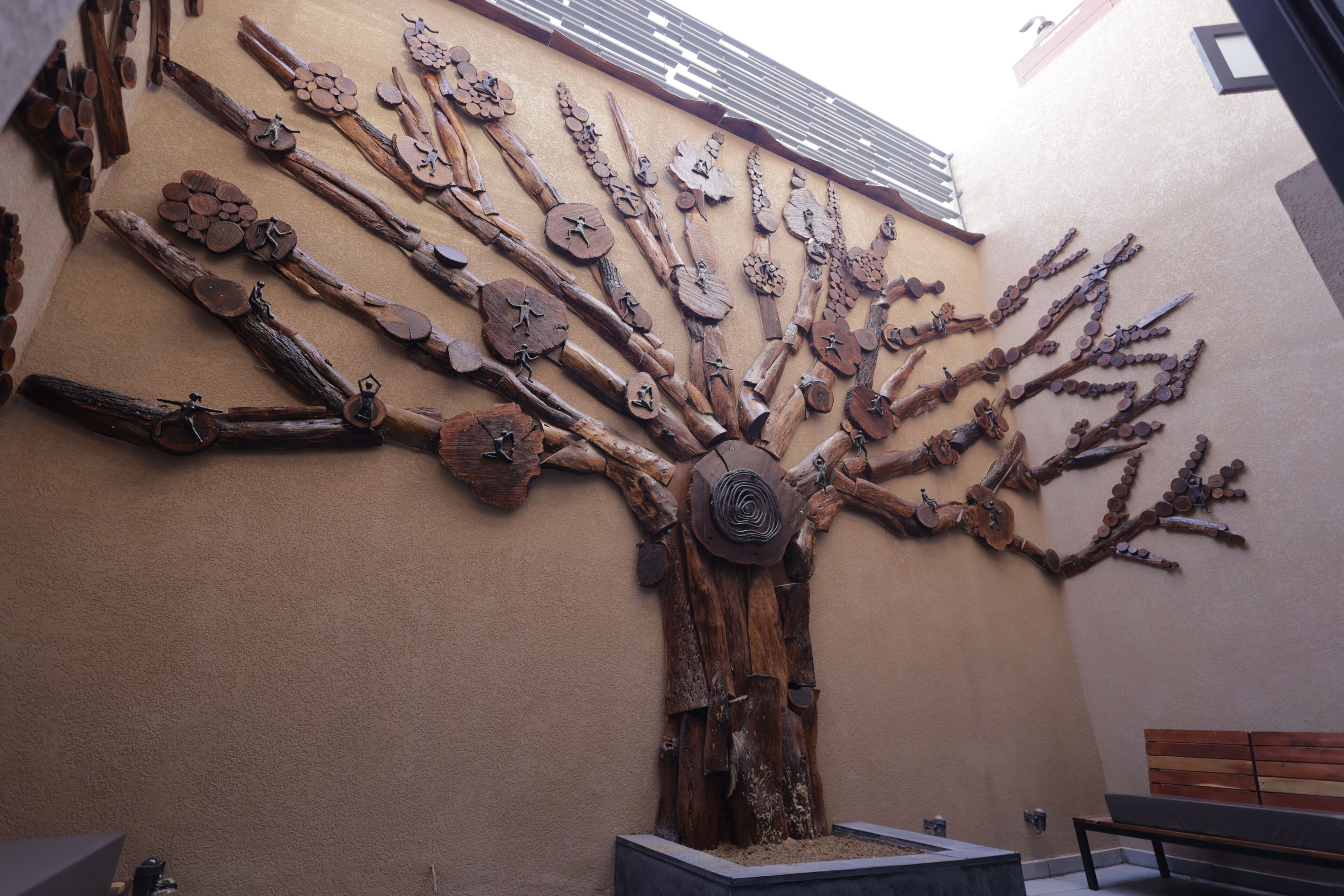 A wall art installation resembling a tree with branches and leaves made of wood and metal.