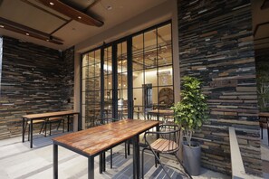 A modern interior with wooden tables and chairs, stone walls, and large windows. - Nook & Corner - A Peaceful 2-bedroom bed & breakfast with AC for a relaxing stay (Unknown)