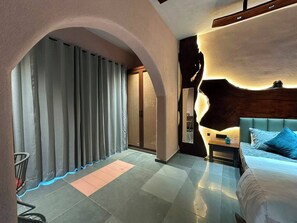 Ein modernes Hotelzimmer mit einem großen Bett, einem Nachttisch und einer Wandgestaltung mit bogenförmigen Elementen.