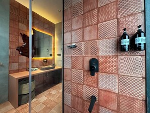 A modern bathroom with patterned tiles, a glass shower enclosure, a sink, and two bottles of shampoo. - Nook & Corner - A Peaceful 2-bedroom bed & breakfast with AC for a relaxing stay (Unknown)
