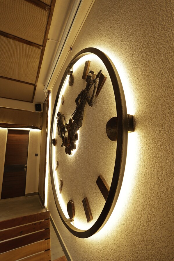 A wall-mounted clock with a circular frame and illuminated numbers.