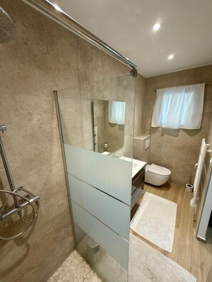 A modern bathroom with a glass shower enclosure, a white toilet, and a glass vanity.