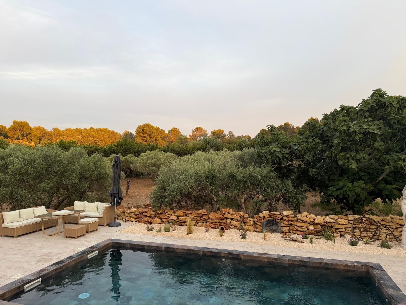 Una piscina con pared de piedra y zona de estar al aire libre.