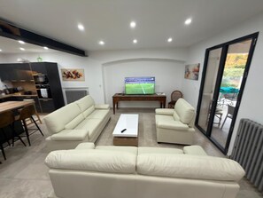 A modern living room with a sofa set, a coffee table, and a television displaying a sports game.