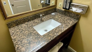 A bathroom with a granite countertop sink, a mirror, a hairdryer, and a towel rack. - Cozy 2 Queen Suite 123–Stroll Historic Downtown Great Restaurants & Unique Shops (Grants Pass)