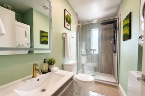 A bathroom with a white sink, a toilet, and a glass shower enclosure. - Biophilic Oasis Knox Henderson (Dallas)