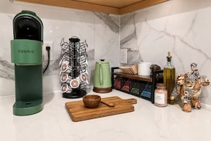 A kitchen with a green Keurig coffee maker, a wooden cutting board, a salt shaker, and a decorative ceramic elephant. - Biophilic Oasis Knox Henderson (Dallas)