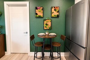A kitchen with a green wall, a stainless steel refrigerator, and a dining table with chairs. - Biophilic Oasis Knox Henderson (Dallas)