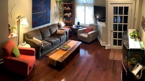 A living room with a sofa, armchairs, a coffee table, and a television. - The Willow House Toronto (Toronto)