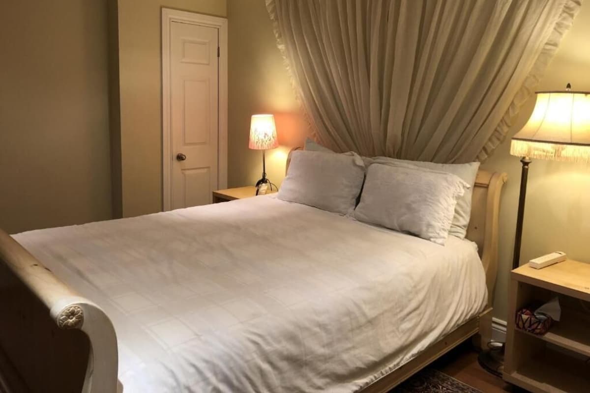 Een slaapkamer met een bed, twee bedlampen, een deur en een nachtkastje.