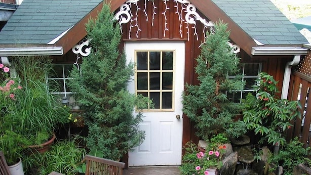 A wooden deck with a table and chairs, a white door, and a small pond with plants and rocks. - The Willow House Toronto (Toronto)