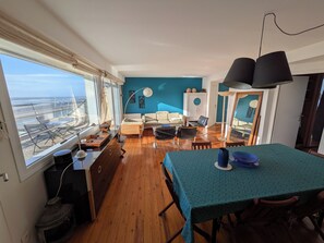 A spacious living area with a large window, a dining table, and a sofa. - Perfect 3-bedroom 2 bathroom apartment right on the waterfront (Wimereux)