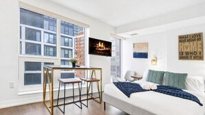 A modern bedroom with a bed, a desk, and a large window. - Eastgate Urban Suites (Toronto)