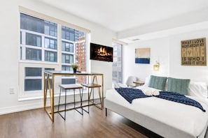 Een moderne slaapkamer met een bed, een bureau en een groot raam.