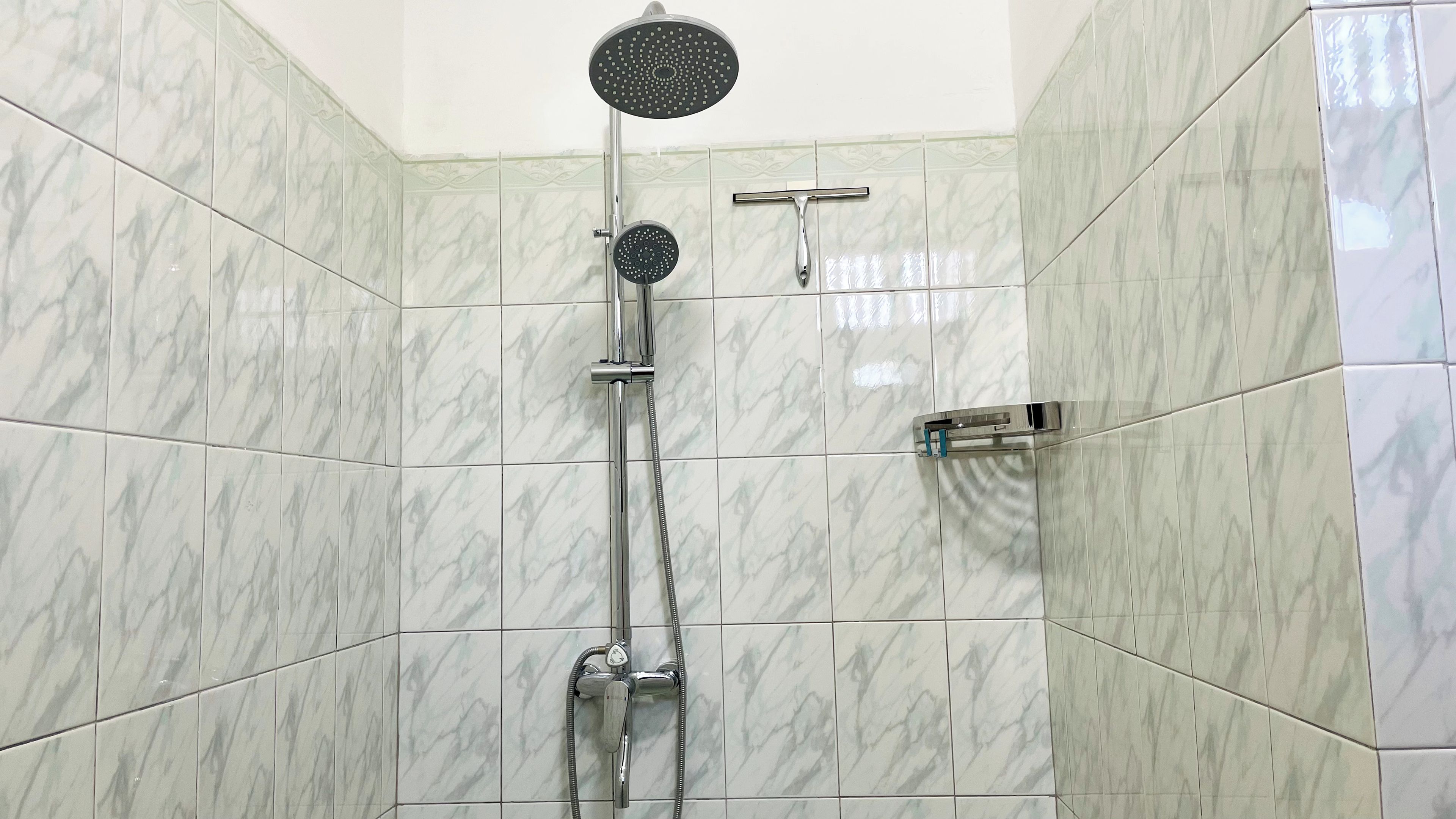 A shower with a handheld showerhead and a wall-mounted rain showerhead.