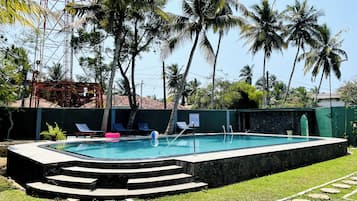 Une piscine avec des marches permettant d’y accéder, entourée de palmiers et d’un mur végétal.