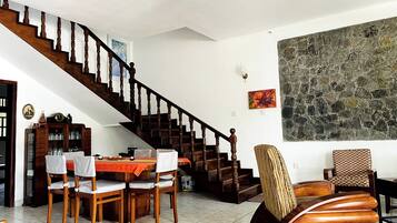 A dining area with a wooden staircase, a table set for two, and a large abstract painting on the wall.