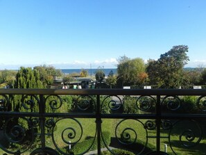 A balcony with a wrought iron railing overlooking a landscaped garden and a distant view of the sea. - Villa Bella, First row With sea View (Heringsdorf)
