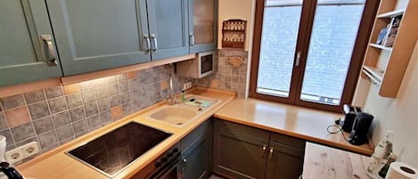 A compact kitchen with a sink, stove, and cabinets.